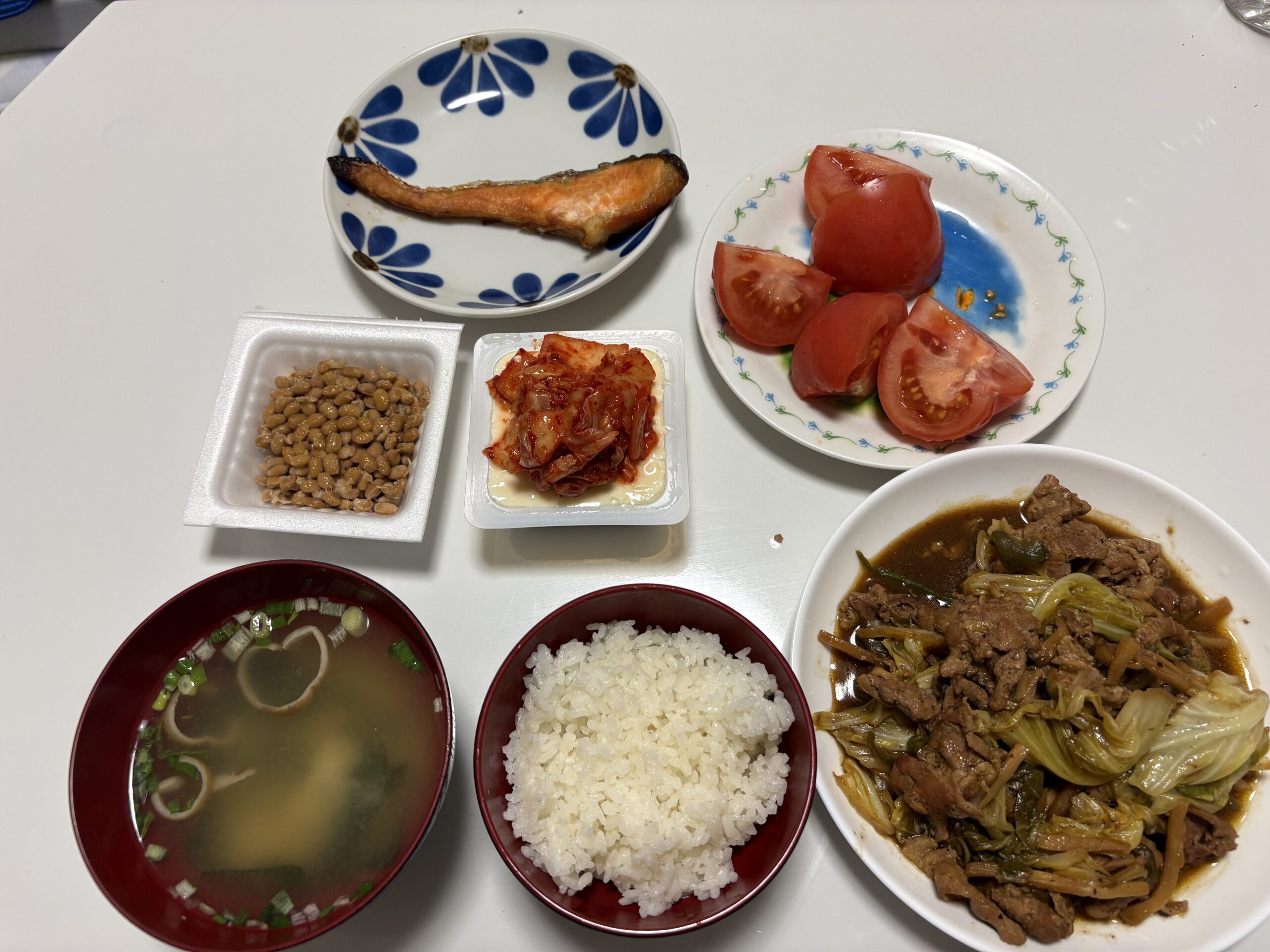 夜ごはん一式。味噌汁、納豆、キムチ、焼き鮭、ご飯、トマト、肉と白菜の煮込み