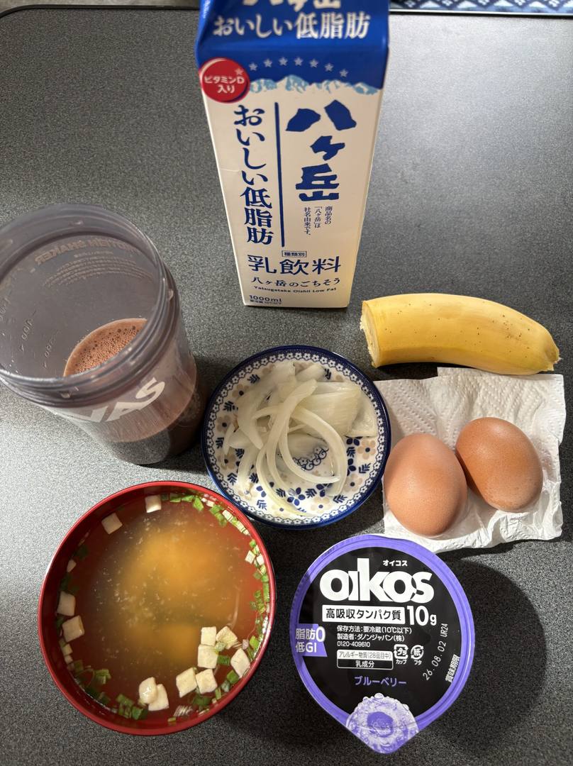 朝ごはん一式。プロテイン、低脂肪乳、バナナ、酢玉ねぎ、卵2個、豆腐の味噌汁、オイコスのヨーグルト